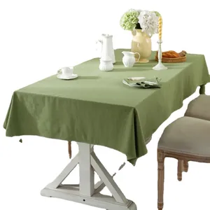 Minimalist sage green cotton tablecloth with natural texture on a white wooden dining table