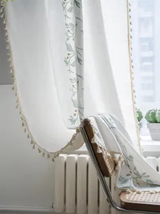 Detail of green leaf embroidery and cream beige fringe tassels on semi-sheer linen curtain