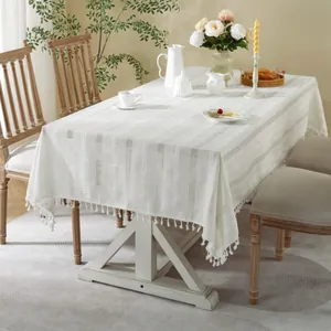 Detail of cream jacquard tablecloth featuring vertical weave and spherical tassel edges