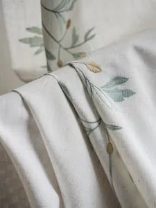 Macro view of green floral embroidery on premium beige cotton linen curtain fabric