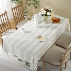 Detail of cream rectangle tablecloth featuring vertical stripes and braided fringe tassels
