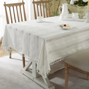 Close-up of white striped openwork tablecloth with decorative braided tassels