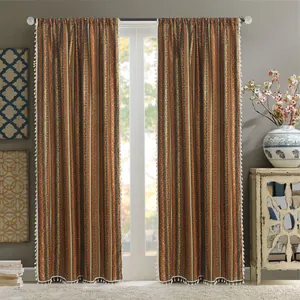 Detail of bohemian cotton linen curtain featuring golden stripes and white fringe tassels