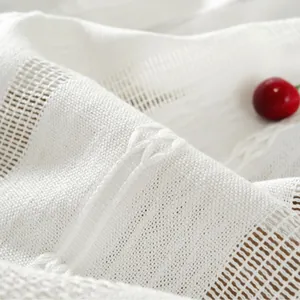 Close-up of white jacquard lace tablecloth with intricate hollow knit and braided texture