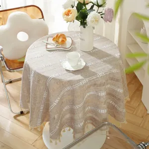 Close-up of beige jacquard round tablecloth with geometric patterns and tassel fringe
