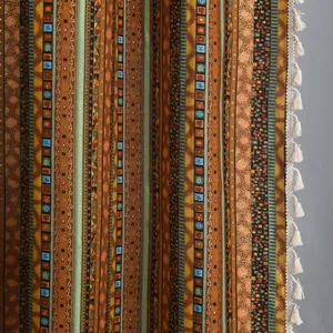 Detail of bohemian cotton linen curtain featuring gold stripes and white fringe tassels