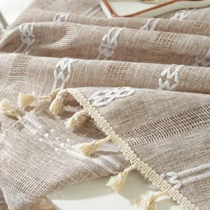 Detailed close-up of textured linen tablecloth fabric with boho embroidery and tassels