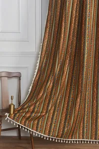 Detail of bohemian cotton linen curtain with vintage stripes and white tassel trim