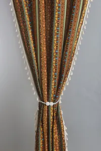 Detailed close-up of Bohemian cotton linen curtain with stripes, tassels and pearl tieback
