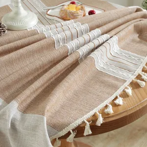 Macro detail of khaki textured tablecloth with woven patterns and white fringe tassels