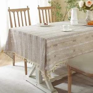 Beige striped jacquard tablecloth with tassel fringe on a wooden dining table scene