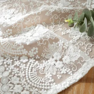 Gros plan de broderie de dentelle florale blanche sur tissu en maille transparente