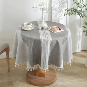 Detail of grey and white striped round tablecloth featuring decorative cotton ball tassels