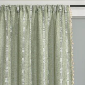 Detailed texture of green linen curtain with white geometric patterns and tassel trim