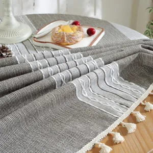 Close-up of linen-style table runner with white wave embroidery and handmade tassels