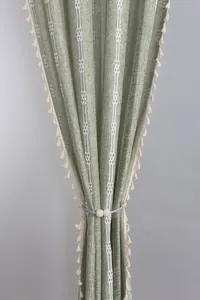 Detail of green linen textured curtain with white geometric stripes and magnetic pearl tieback