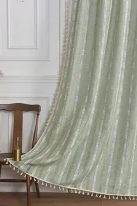 Close-up of sage green jacquard curtain with white stripes and cream fringe tassels