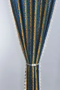Detail of bohemian striped cotton linen curtain with tassels and pearl magnetic tieback