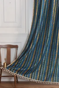 Detail of Bohemian curtain with gold stripes and white cotton tassels on a vintage chair