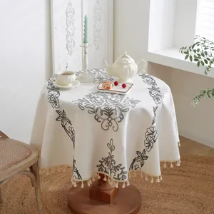 Bordado detallado y borlas beige en un mantel redondo de jacquard nórdico