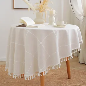 Macro detail of round beige tablecloth with diamond quilting and decorative fringe