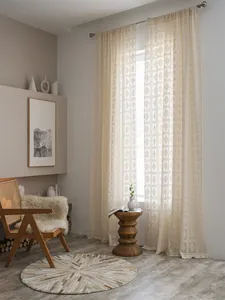 Dettaglio macro della tenda all'uncinetto beige con motivi geometrici a rombi e trama