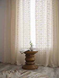 Dettaglio tenda beige all'uncinetto con motivi geometrici a rombi e trama traforata
