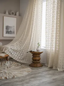 Dettaglio della tenda all'uncinetto color crema con motivi a rombi e luce soffusa filtrante