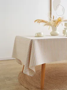 Detail van een gestreept tafelkleed met kwastjes en minimalistisch huisinterieur