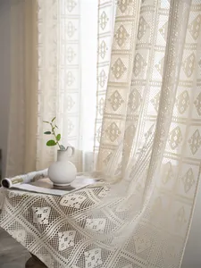 Dettaglio della tenda in pizzo beige all'uncinetto con trama geometrica a rombi