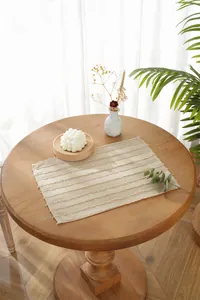 Detail of beige rectangular placemat with horizontal fringe on a wooden table