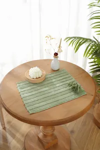 Detail of light green rectangular placemat with 3D striped texture and frayed edges