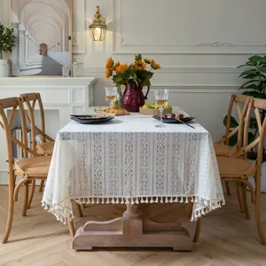 Close-up of elegant beige lace tablecloth featuring floral hollow embroidery and tassels