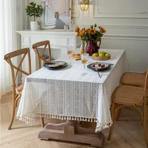 Close-up of beige crochet lace tablecloth with geometric patterns and fringe edges