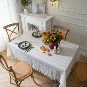 Close-up of beige lace tablecloth featuring hollow patterns and decorative tassels