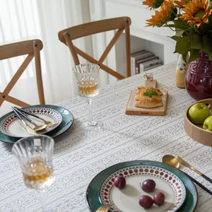 Close-up of white crochet lace tablecloth with floral hollow patterns on a wooden table