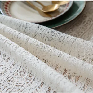 Close-up of beige lace tablecloth with intricate floral cutouts and tassel details