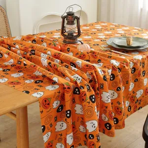 Detail of Halloween tablecloth featuring spooky pumpkins, ghosts, and skulls on a wooden table