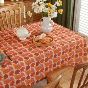 Detailed view of autumn maple leaf tablecloth on a dining table with cozy home decor