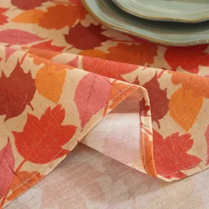 Close-up of maple leaf print linen tablecloth with detailed stitching and ceramic plate