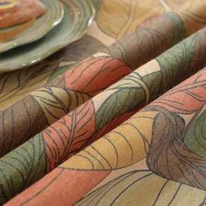 Close-up of linen fabric showing maple leaf print texture and autumn dining table detail