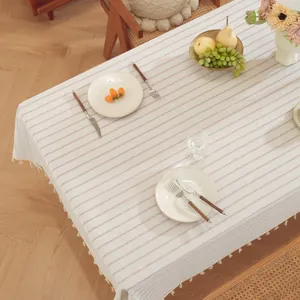 Detail van linnen gestreept tafelkleed met beige franjes op een rustieke houten tafel