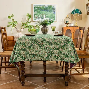 Detail of green floral jacquard tablecloth with daisy pattern on a vintage wooden table