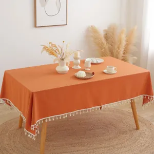 Detailweergave van pompoenoranje katoenen linnen tafelkleed met witte sierkwastjes