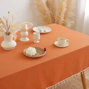Minimalistisch oranje katoenen tafelkleed met witte kwastjes in een Scandinavische stijl