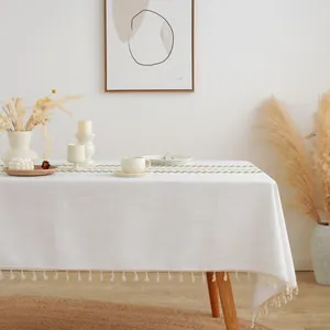 Close-up of bohemian white tablecloth with green woven stripes and decorative tassels