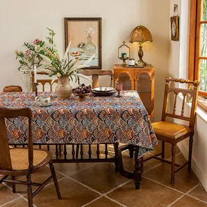 Detail of bohemian jacquard tablecloth with orange and blue feather patterns in a dining scene