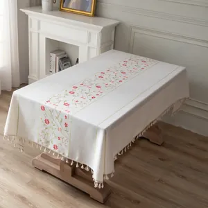 Close-up of floral embroidery and tassel fringe on a rectangular cotton linen tablecloth