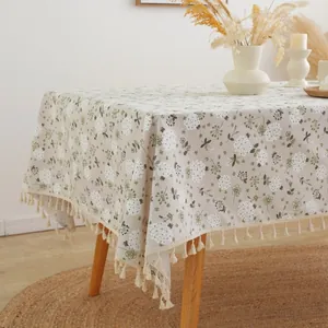 Detail of floral linen tablecloth with white hydrangea patterns and cream fringe tassels