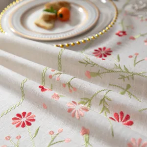 Close-up of floral embroidery on rustic linen tablecloth with elegant dinnerware